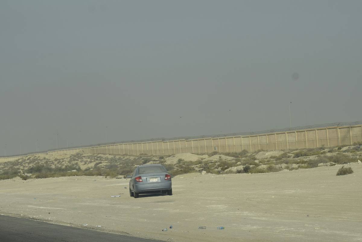 A single car drives on a dusty road.