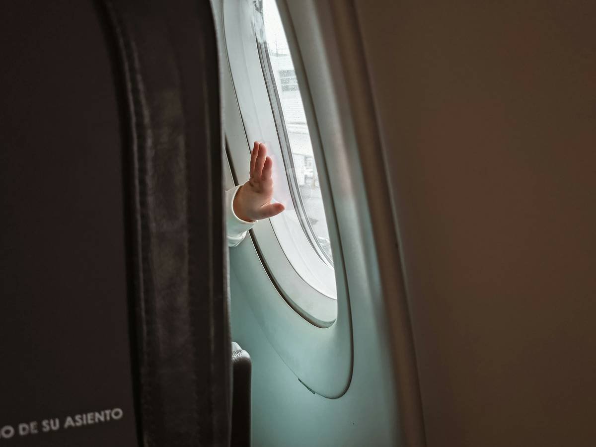 First time traveler placing her hand on an aircraft window.